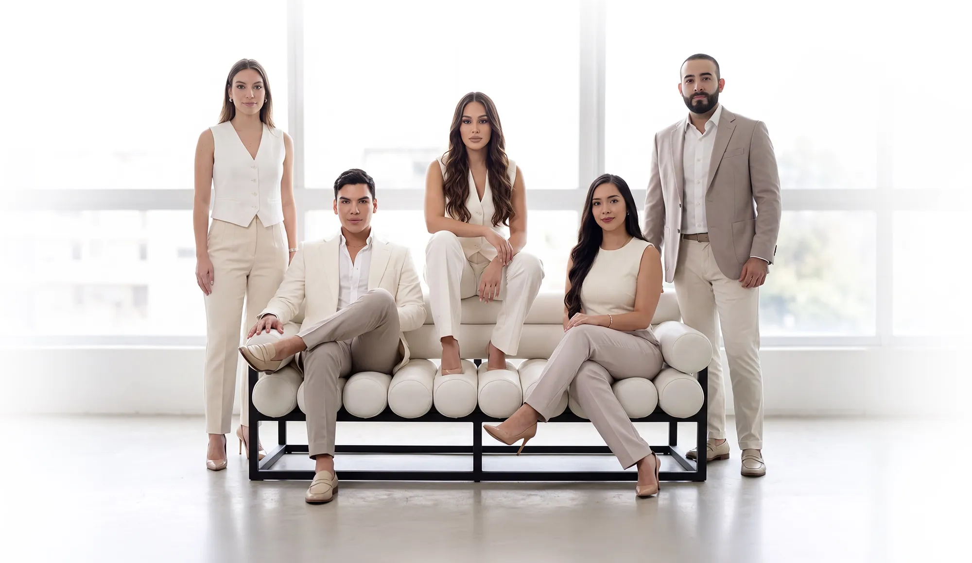 El equipo de Clínica Santa María, cinco profesionales vestidos en tonos claros, en torno a un sofá blanco frente a un gran ventanal
