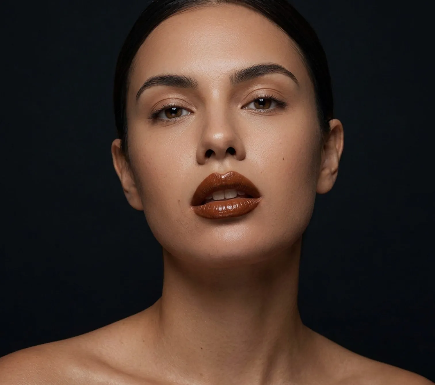Retrato de una mujer de perfil frontal sobre fondo oscuro, con la piel iluminada.